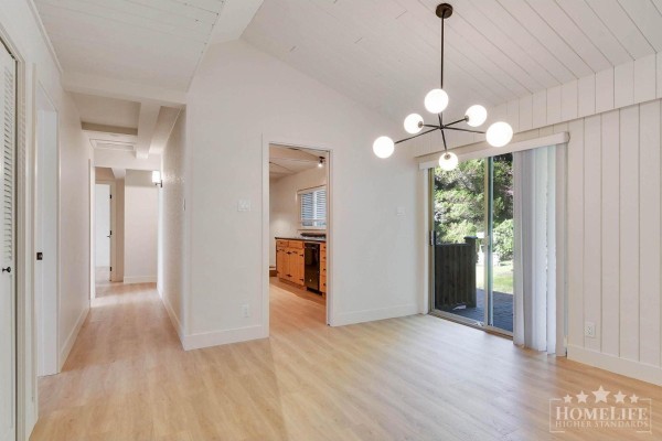 Dining area with vaulted wood-paneled ceiling, modern light fixture, and view into hallway and kitchen. - House 12687 23 Avenue, White Rock