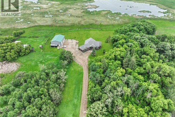 Aerial view of a sprawling acreage with a house, outbuildings, and dense forest. - Holars Haven Acreage, Spy Hill Rm No  152