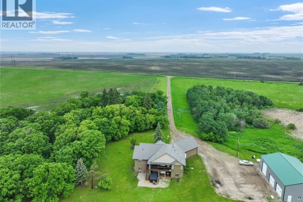 Aerial view of a home situated amidst lush green trees and expansive agricultural fields. - Holars Haven Acreage, Spy Hill Rm No  152