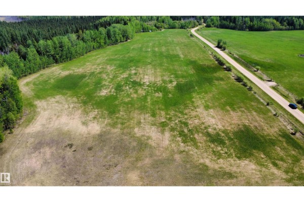 Aerial view of a cleared green field next to a gravel road and forest. - Hope Lake Nw-33-65-18-w4, Rural Athabasca County