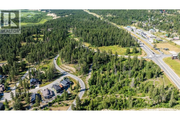 Aerial perspective of a wooded lot with a residential street curving through it, bordered by forest and a main highway. - Hot Springs Road Lot# 5056a, Fairmont Hot Springs