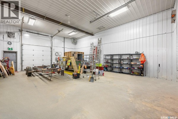 Interior of commercial bay with concrete floor, white metal walls, and overhead garage door. - Hwy 11 Bays, Lumsden Rm No  189