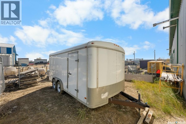 White tandem axle cargo trailer parked outdoors beside a commercial building with blue sky. - Hwy 11 Bays, Lumsden Rm No  189