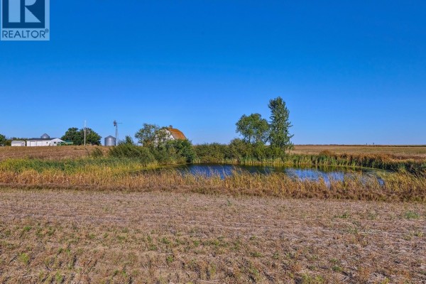Long gravel driveway leading to a white house and barn in a rural landscape. - Imlach Acreage, St  Andrews Rm No  287