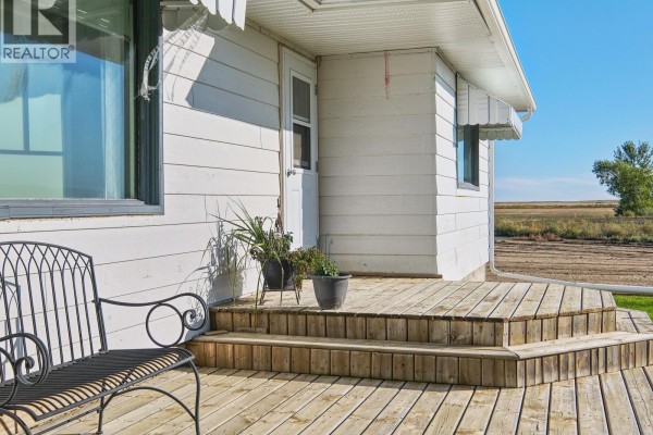 Small pond with dry reeds in a rural landscape with a house in the distance. - Imlach Acreage, St  Andrews Rm No  287
