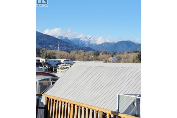 View from a balcony of a metal roof and mountains in the background. - Jnw33 415 W Esplanade, North Vancouver