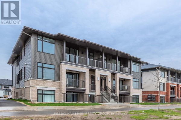 Side exterior view of a modern townhouse building with beige brick and grey siding. - K - 50 Jaguar Private, Ottawa