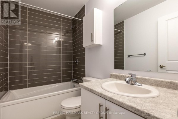 A bathroom with a white bathtub, toilet, and vanity with a beige speckled countertop. - K - 50 Jaguar Private, Ottawa