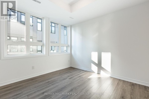 A bright, empty room with white walls, grey wood-look flooring, and large windows. - K - 50 Jaguar Private, Ottawa