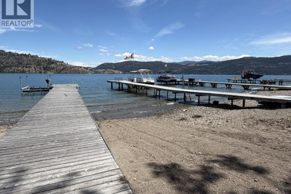 Wooden dock with several boats moored on a sunny day with hills in the distance. - Ki Low Na Road Lot# 4, Vernon