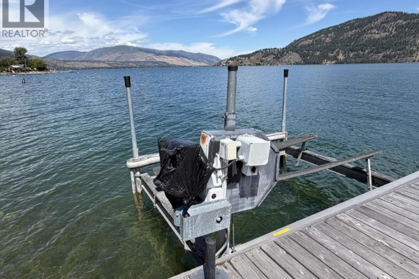 Close-up of a boat lift with a black cover on a wooden dock extending into the lake. - Ki Low Na Road Lot# 4, Vernon