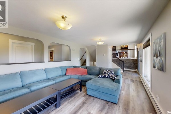 Spacious living room with a large blue sectional sofa, dark coffee tables, and arched doorways. - Kindersley Acreage, Kindersley Rm No  290
