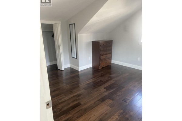 Bedroom with dark wood floors, a dresser, a mirror, and a closet. - Laneway House 3436 Tanner, Vancouver
