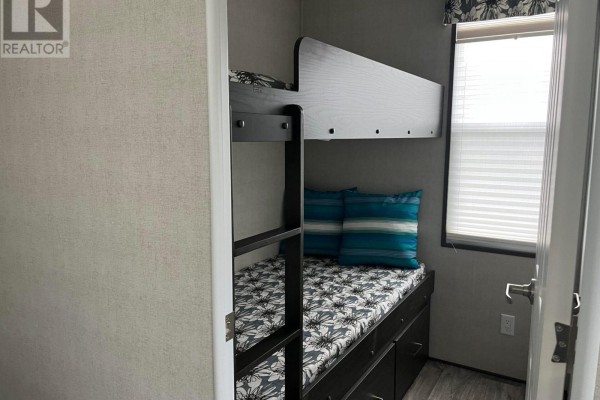 Bunk beds with blue and green striped pillows and a window with blinds. - Lkr026 - 1047 Bonnie Lake Camp Road, Bracebridge