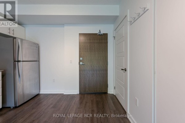 Interior view of an apartment showing a stainless steel refrigerator and two doors. - Ll02 - 25 Kay Crescent, Guelph