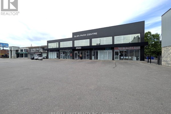 A left-to-right view of the commercial building's exterior showing multiple businesses and surrounding asphalt. - Ll1 - 2920 Dufferin Street, Toronto
