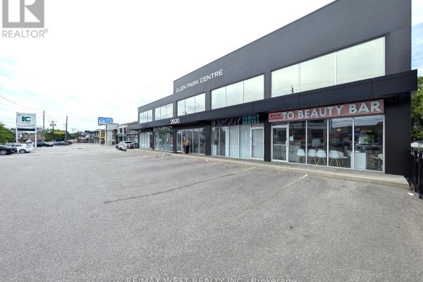 Close-up view of storefronts including a pharmacy, dental office, and beauty bar within the commercial building. - Ll1 - 2920 Dufferin Street, Toronto