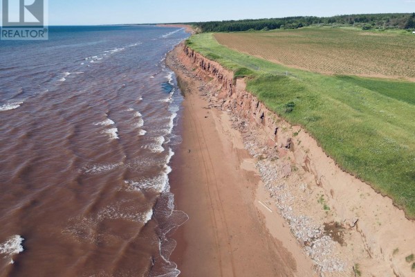Aerial view of coastline with cliffs, sandy beach, and farmland in the distance. - Lot 06-2 Route 14, Campbellton