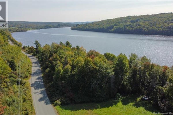 Aerial view of a river flanked by dense forest and a winding road under a blue sky. - Lot 09-01 Route 105, Southampton