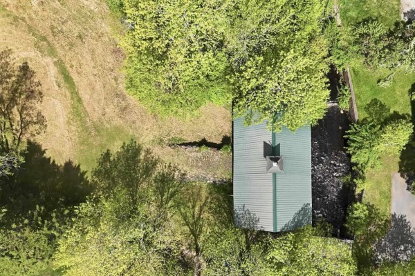 A large, grassy clearing is surrounded by mature trees under a partly cloudy sky. - Lot 11 Kinburn Street, Mahone Bay