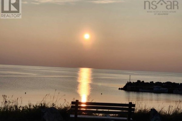 Sunset over the ocean viewed from Lot 12 Highway 337, Antigonish County, with a bench in the foreground. - Lot 12 Highway 337, Livingstone Cove