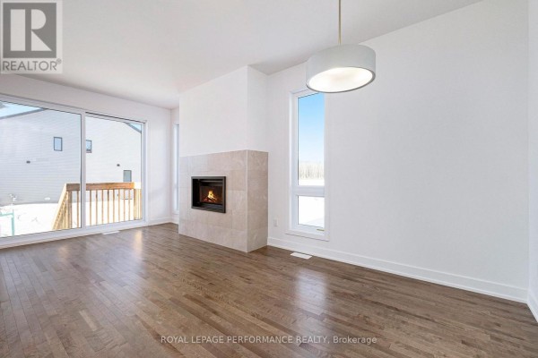 Living room with hardwood floors, white walls, a modern fireplace, a large sliding glass door with wooden deck view. - Lot 149 Bourdeau Boulevard, The Nation