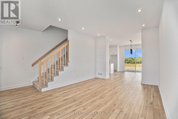 Open-concept living area with light hardwood floors, white walls, and a staircase leading upstairs. - Lot 150 Bourdeau Boulevard, The Nation
