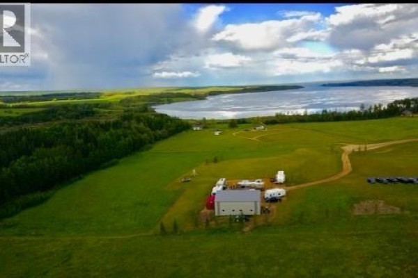 Aerial view of a lake surrounded by green fields and trees, with buildings and RVs. - Lot 2 - 70539 Rng Rd 250, Rural Greenview No  16, M D  Of
