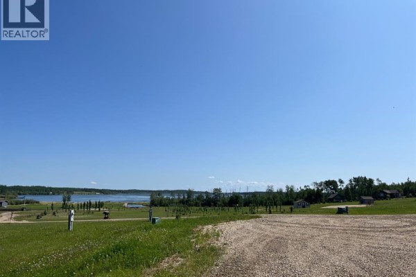 Gravel driveway leading through green grass towards a wide view of a calm lake. - Lot 2 - 70539 Rng Rd 250, Rural Greenview No  16, M D  Of