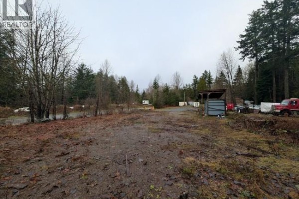 Cleared land with scattered trees and debris, featuring a shed and parked vehicles. - Lot 2 Squamish Valley Road, Squamish