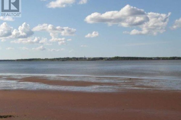 View of a sandy beach with low tide, distant land visible under a clear sky. - Lot 2 Treasure Lane, Port Hill