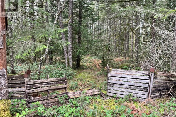Weathered wooden structures, possibly fences or pallets, sit in a forest clearing. - Lot 2 Walker Rd, Duncan