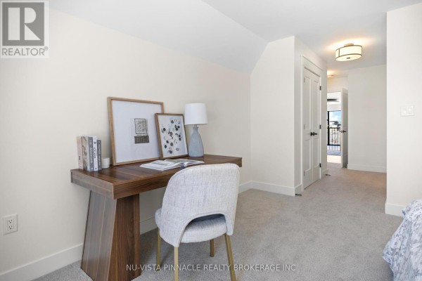 A home office with a wooden desk, upholstered chair, and framed artwork on the wall. - Lot 20 Harvest Lane, Thames Centre