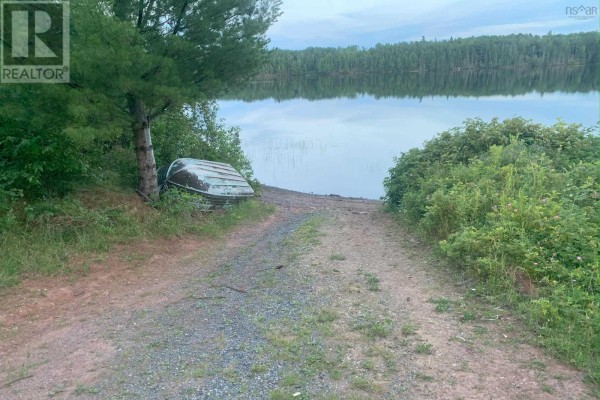 Gravel road leads to a calm lake with an overturned rowboat on shore. - Lot 21 Black Lake Road, Black Lake