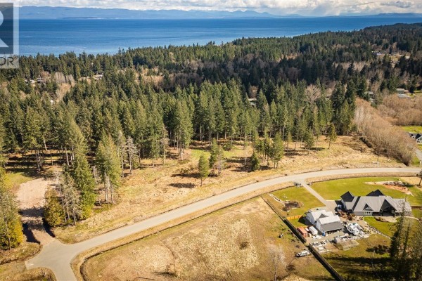 Aerial view of a large wooded lot with a paved road and houses in the distance. - Lot 21 Oyster River Way, Black Creek