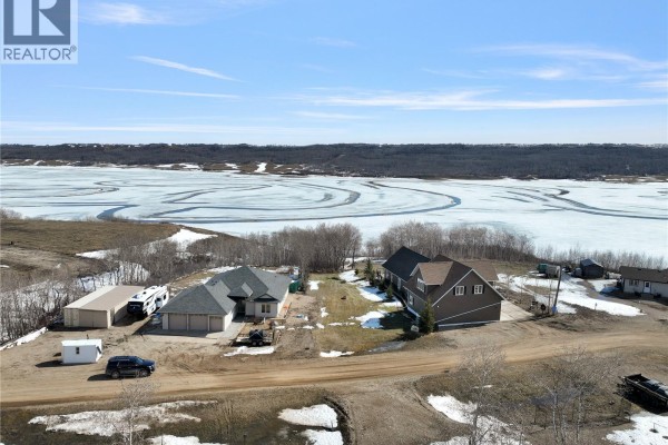Aerial view of multiple residential properties and outbuildings on a dirt road with a large frozen body of water. - Lot 21 Pelican Landing, Lake Of The Prairies