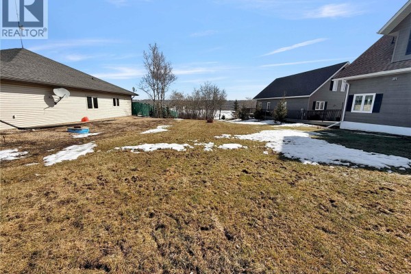 Ground-level view of a grassy lot with melting snow patches, surrounded by residential homes. - Lot 21 Pelican Landing, Lake Of The Prairies
