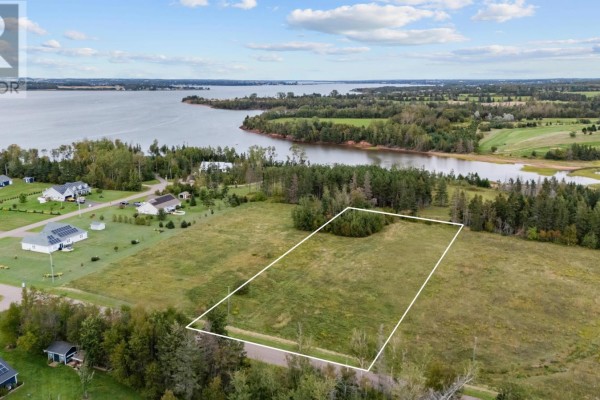 Aerial view of a grassy lot outlined in white, showing nearby houses and water. - Lot 22-2 Macphail Cove Road, Fairview