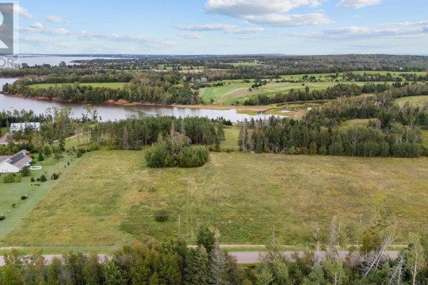 Aerial view of a large grassy lot with trees and a body of water in the distance. - Lot 22-2 Macphail Cove Road, Fairview