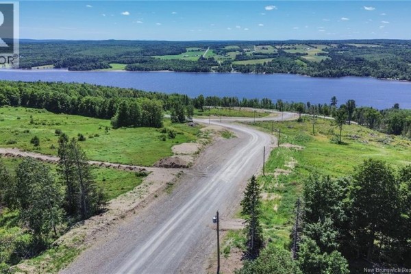 Winding road with surrounding trees and open land, overlooking a river and hills in the distance. - Lot 22-35 Route 616, Keswick Ridge