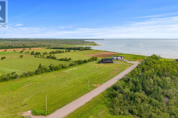 Aerial view of a coastal property with green fields, scattered homes, and a treed shoreline. - Lot 22-6 Lorraine Lane, Mount Stewart
