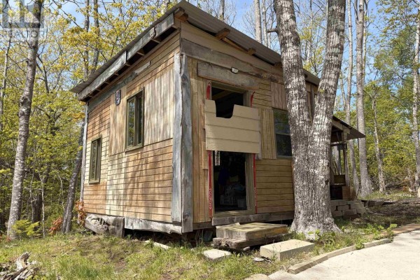 Exterior of a small, rustic wooden cabin surrounded by trees. - Lot 23-3 155 Wallace Bridge Station Road, Wallace River West