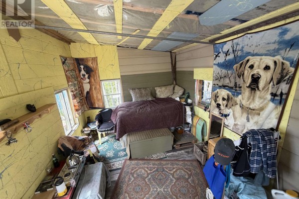 Interior of a small cabin with a bed, rugs, and dog-themed tapestries. - Lot 23-3 155 Wallace Bridge Station Road, Wallace River West