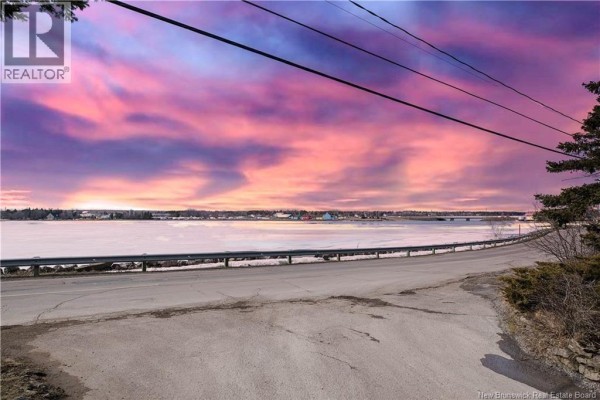 Frozen body of water with a road in the foreground and a colorful sunset sky. - Lot 23-a Riverside Drive, Shediac