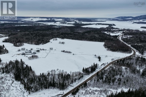 Aerial view of a rural road winding through snow-covered fields and trees, with a frozen body of water in the distance. - Lot 24-1 Rankinville Road, Mabou