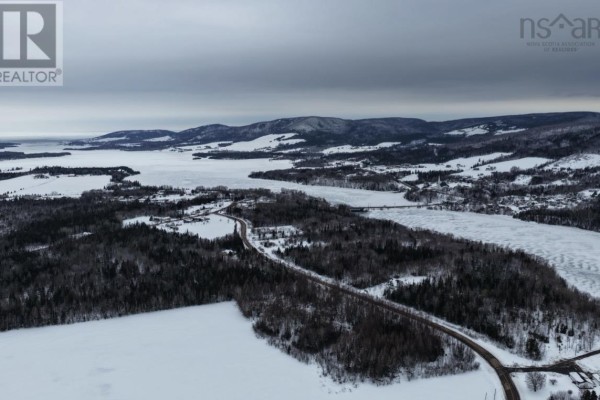 Aerial view of a vast, snow-covered valley with a road, scattered houses, and hills under a cloudy sky. - Lot 24-1 Rankinville Road, Mabou