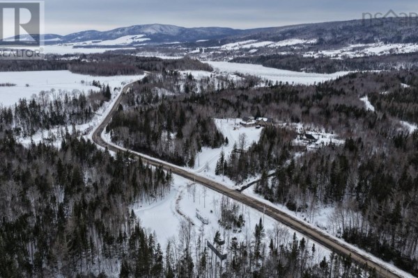 Drone shot of a rural road passing through a forested area with snow-covered fields and houses. - Lot 24-2 Rankinville Road, Mabou