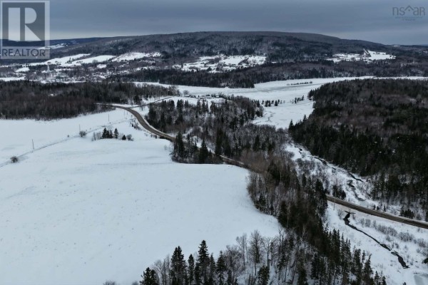 Winding road through snow-covered fields and trees with hills in the background. - Lot 24-3 Rankinville Road, Mabou