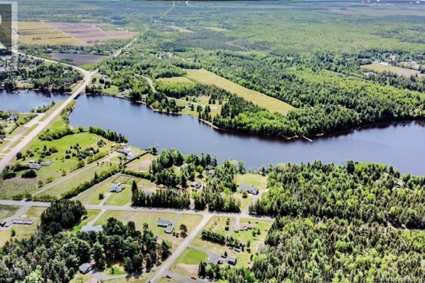 Aerial view of a property with a mix of wooded areas, a clearing, a lake, and several buildings. - Lot 25-1 St-charles N, Saint Charles