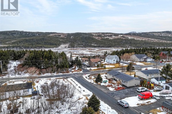 Expansive view of a coastal town with houses, water, and forested hills under a cloudy sky. - Lot 28 Shaheen Crescent, Come By Chance